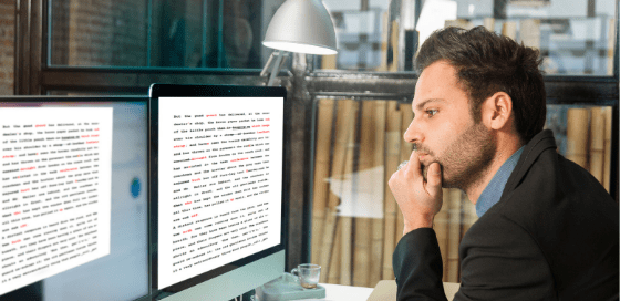 Man proofreading a document at a computer