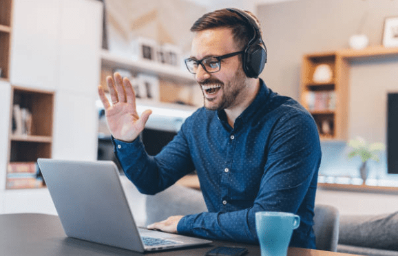 person looking at a laptop smiling and waving