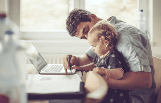 Father working on computer with child on lap