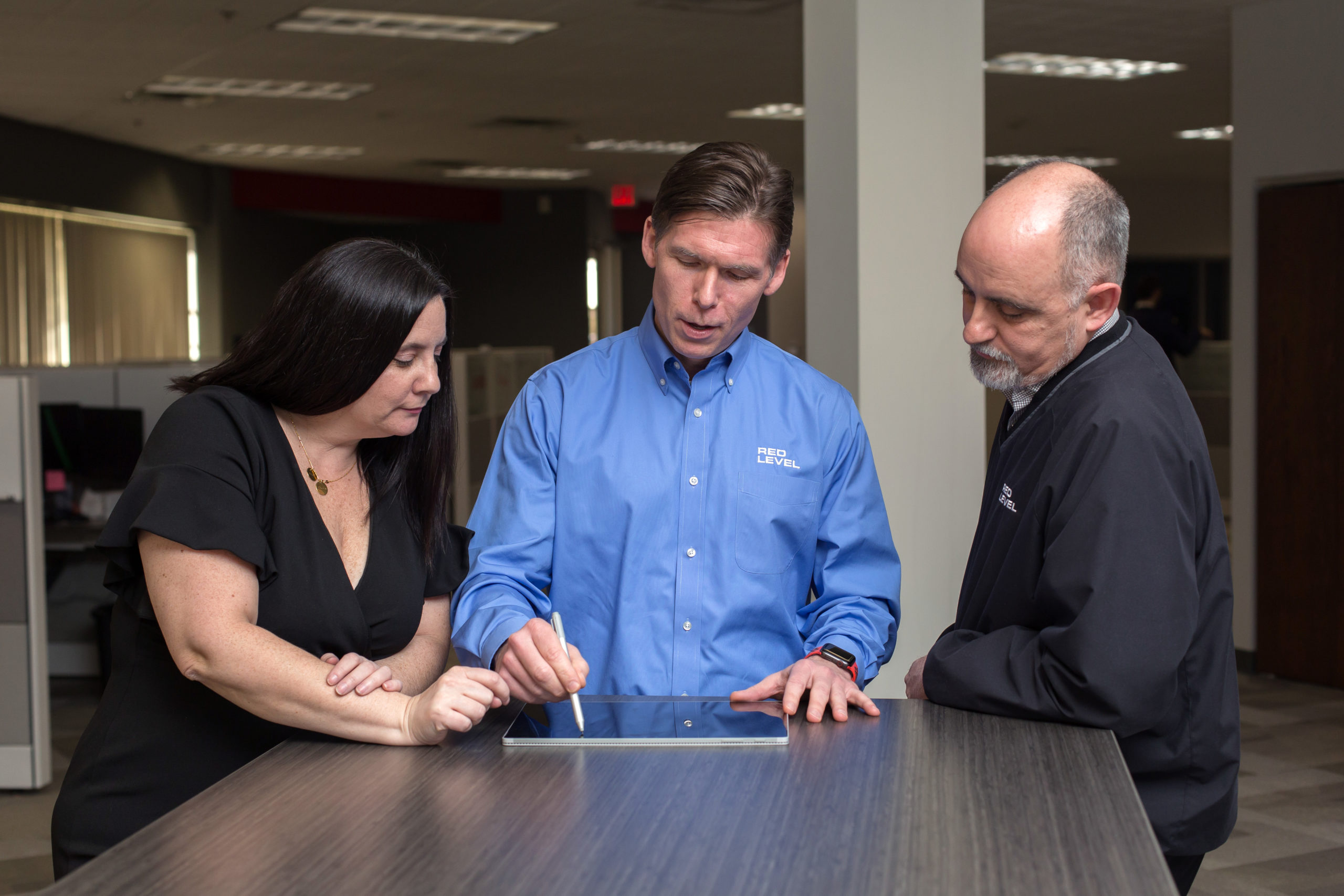 three employees collaborating on a tablet